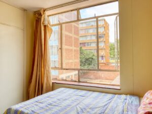 A comforting bedroom with a view of the urban exterior through a large window.